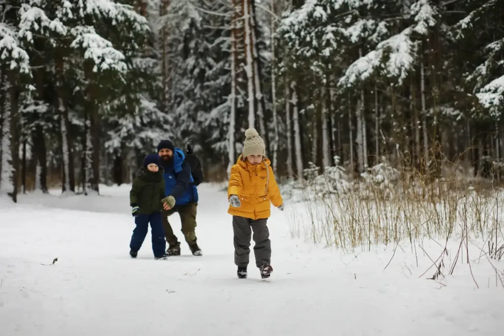 Rodzina spacerująca zimą po ośnieżonym lesie – zimowe wycieczki z dziećmi w Tatry